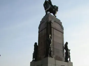 Monument to General Carlos M. de Alvear with a dark equestrian statue atop a tall stone pedestal and standing figures at the base
