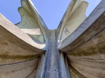 The Stone Flower monument rises in concrete petal-like forms against a clear blue sky.
