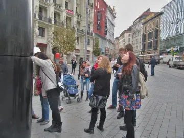 The Brno astronomical clock stands in a busy square with a crowd of people gathered around it.