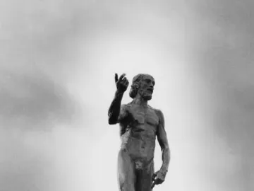 Saint John the Baptist sculpture of a bearded nude man raising one arm and pointing upward.
