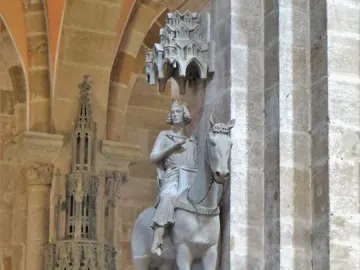 The Bamberg Horseman mounted on a horse and displayed high on a bracket inside a Gothic cathedral interior.