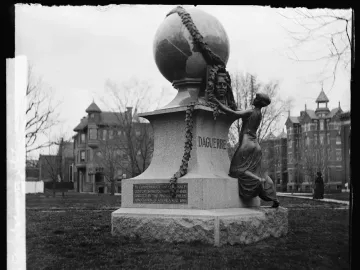 Daguerre Memorial with a globe at the top and a kneeling bronze figure at the base