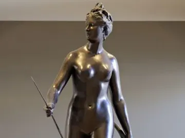 Bronze statue of Diana holding a bow and arrow in a twisting pose.