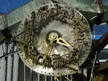 Close-up of the Hornsby Water Clock face with brass hands, bronze letters, and decorative animal figures around the rim.