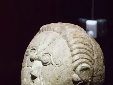 Mšecké Žehrovice Head, a carved stone head with stylized eyes, a prominent nose, and patterned hair and cheek details.