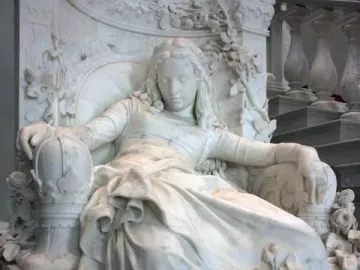 Sleeping Beauty sculpture of a reclining woman in a decorated armchair with roses and foliage