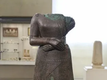Headless statue of Napir-Asu with hands folded across the waist and a long patterned garment.