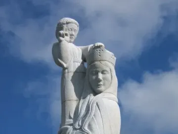 Detail of Our Lady of the Isles showing a crowned, veiled figure supporting a smaller figure against a blue sky.