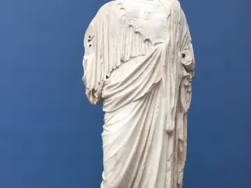 Athena Giustiniani marble statue shown as a headless, armless torso with flowing robes and a circular emblem on the chest.