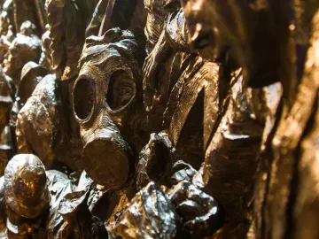 Bronze relief sculpture detail on the Battle of Britain Monument, showing a gas mask among textured figures.