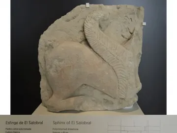 El Salobral sphinx sculpture displayed on a white pedestal with a museum information plaque below it.