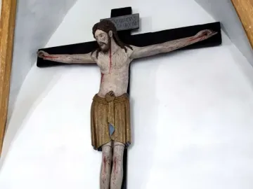 Enghausen Cross showing a painted wooden crucifix with Christ on a dark cross and a plaque above his head.