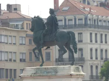Louis XIV equestrian statue on a stone pedestal in Place Bellecour, with city buildings in the background.