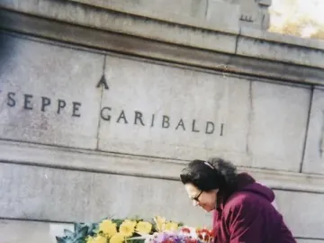A woman arranges a floral wreath at the base of the Garibaldi monument in Rome.