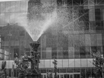 La Joute fountain sculpture spraying water in front of a modern glass building