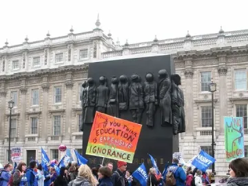 Monument to the Women of World War II partially covered by a protest banner in Whitehall, London.
