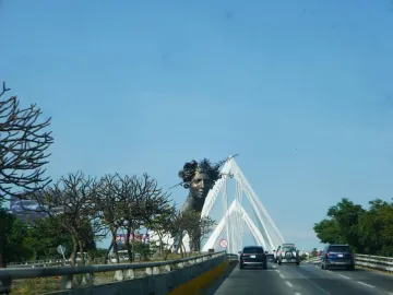 Reminiscencia, a dark bust of a woman with a spiky crown beside a white bridge structure.