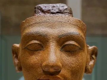 Unfinished head of Nefertiti with closed eyes and a rough top edge.