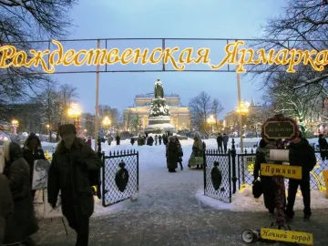 Catherine II Monument in a snowy square with people walking nearby at dusk.