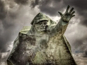 Kościuszkowców Memorial bronze figure with raised hand against a cloudy sky