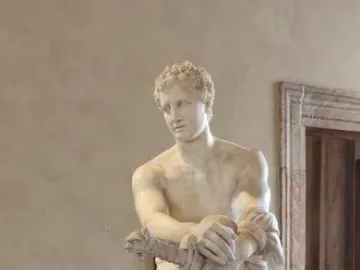 Ludovisi Ares seated in white marble, with a small winged child at his leg and a shield beside him.