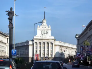 The Statue of Sofia on a tall dark column against a clear blue sky, with a streetlight in front.