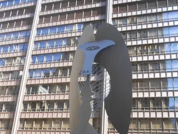 The Picasso abstract sculpture in a plaza beside a tall windowed building, with people gathered around its base.