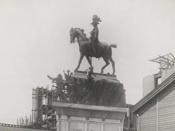 An equestrian statue of Christian IX stands newly erected as several suited onlookers gather below and look up.