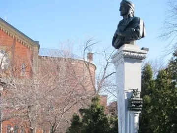 La mort de Dante monument with a dark bust on a tall stone pillar in a snowy park