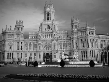 The Cibeles Fountain with a classical figure in a chariot drawn by lions in front of a grand building.