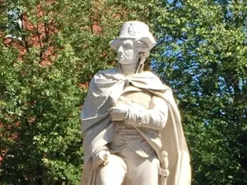 George Washington statue wearing a bicorne hat and draped cloak, set within a small carved boat.