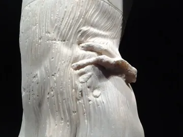 Close-up of the Motya Charioteer showing a marble hand against finely carved draped folds.