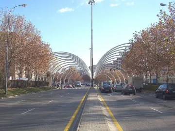 Puerta de la Ilustración spans a Madrid avenue with curved metallic arches over the road and a tall central light pole.