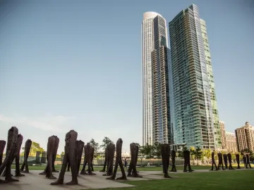 Agora sculptures on a green lawn with Chicago skyscrapers in the background.