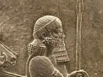 Detail of the Lion Hunt of Ashurbanipal relief showing a bearded figure in profile with a spear and ornate robe.