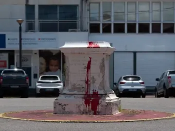 Victor Schœlcher pedestal splattered with bright red paint, standing on a small island in an urban setting.