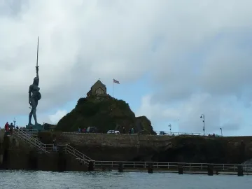 Verity, a dark bronze statue, stands on a stone pier and raises a sword toward the sky.