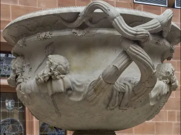 Side view of the Warwick Vase, showing its ornate carved heads and intertwined vine-like handles.