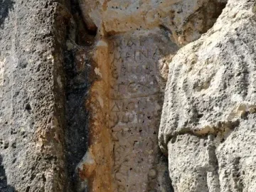 Ancient inscription carved into a weathered rock face beside the Athena relief.