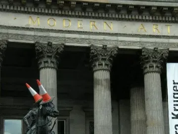 Duke of Wellington statue with two orange traffic cones on the rider’s head in front of the Modern Art building.