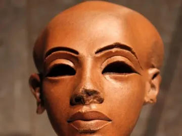Head of a Princess, a reddish-brown stone sculpture with a slender neck, dark almond-shaped eyes, arched brows, and damaged nose bridge.
