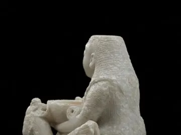 Lady of Galera seated stone figurine holding a bowl, flanked by winged creatures