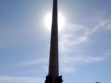 Obelisk of Montevideo silhouetted against the sun with a fountain spraying at its base