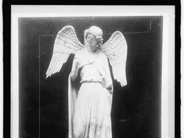 The Smiling Angel statue stands on an ornate arched pedestal, with flowing robes, curly hair, and one hand raised.