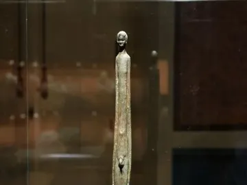 Ombra della Sera bronze figure with a long slender body and detailed head on a black background.