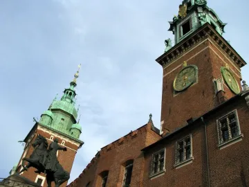 Tadeusz Kościuszko Monument beside a brick building with a green-domed tower at Wawel Castle.