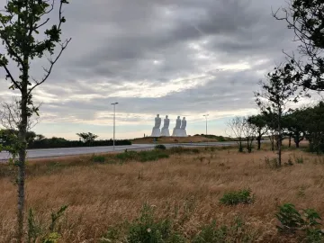 The Man by the Sea sculpture with four large white figures seated on a grassy mound beneath an overcast sky.