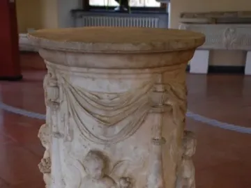 Four Seasons Altar with carved putti and draped decoration on a round marble pedestal.