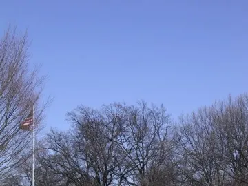 Nathan Bedford Forrest Monument, an equestrian statue on a pedestal in a park with bare trees and a historical marker nearby.