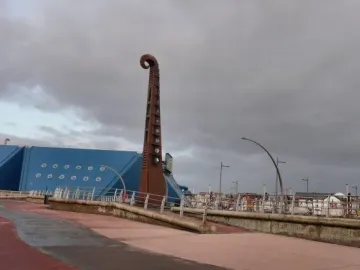 The Blackpool High Tide Organ sculpture beside a blue building on a paved promenade.